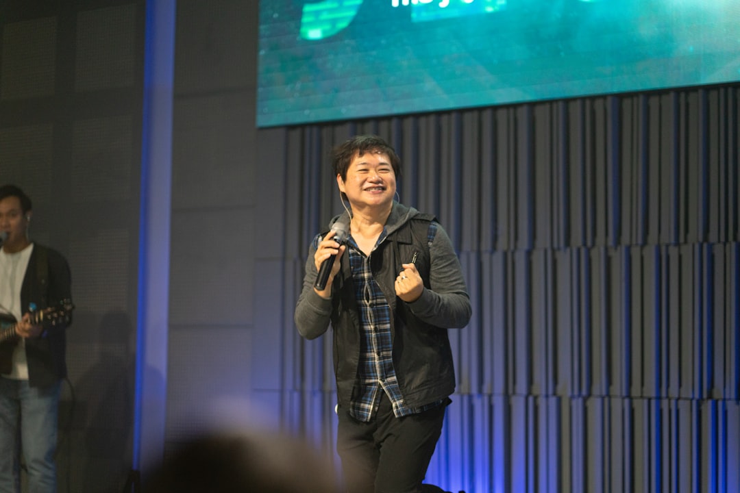 a-man-speaking-into-a-microphone-on-stage-excvj5a1vb4